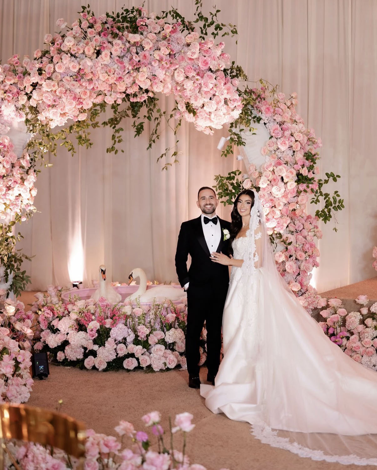 Couple beneath a blush rose arch with swans