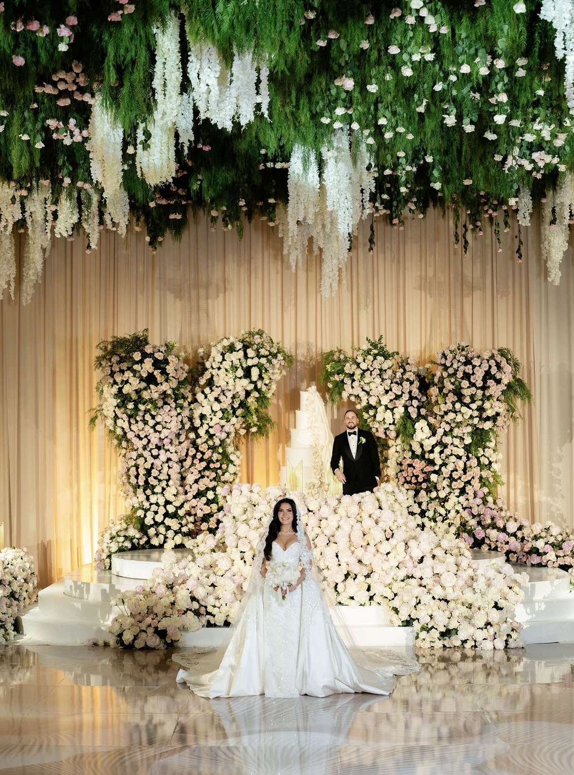 Greenery and blush rose canopy over a couple