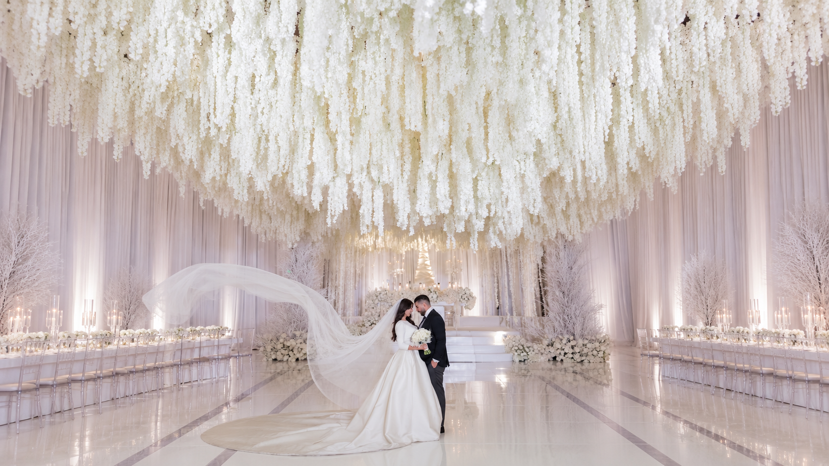 Wedding couple beneath an immersive white floral ceiling by Dolce Fiore